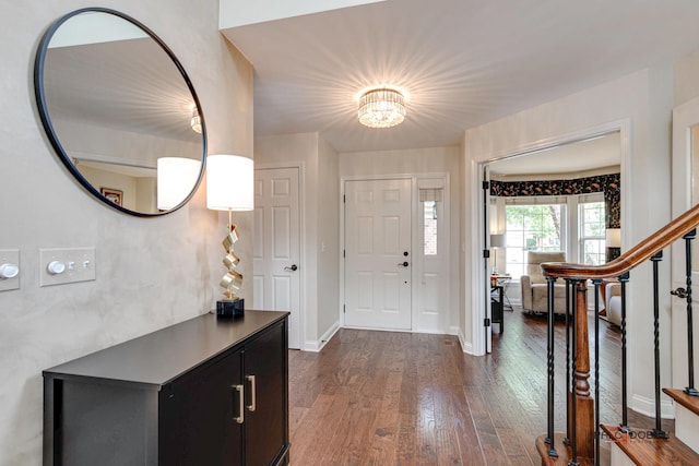 foyer entrance featuring dark wood-style flooring, stairway, and baseboards