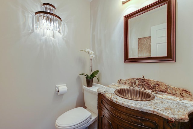 bathroom featuring vanity, toilet, and an inviting chandelier