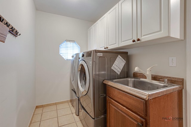 washroom with light tile patterned floors, separate washer and dryer, a sink, baseboards, and cabinet space