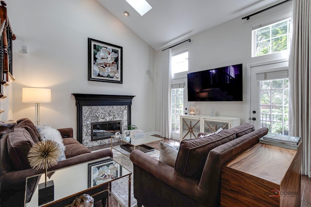 living area with high vaulted ceiling, a skylight, and a fireplace