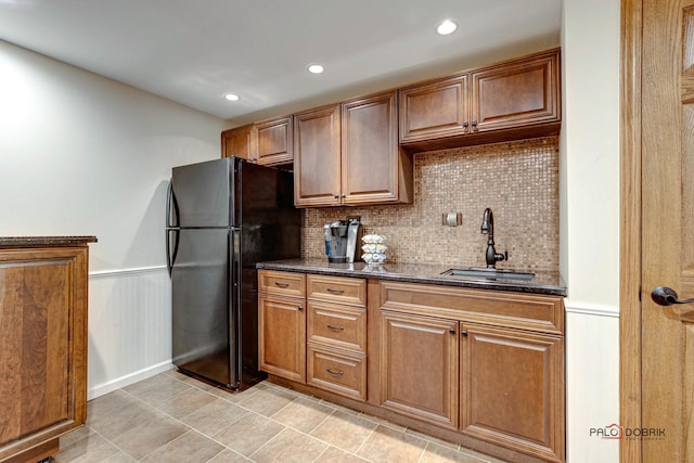 kitchen featuring wainscoting, recessed lighting, a sink, and freestanding refrigerator