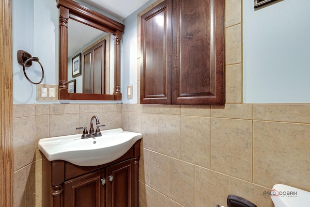 bathroom featuring toilet, vanity, and tile walls