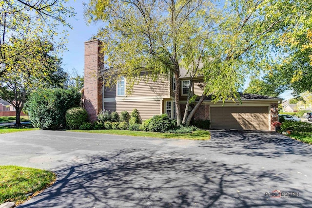 view of front of home with a garage, aphalt driveway, and brick siding