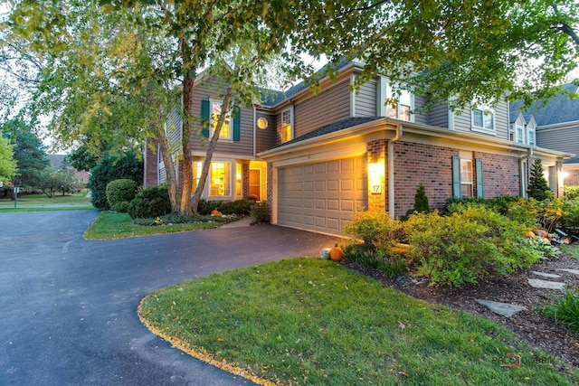 view of front facade featuring aphalt driveway, a front yard, brick siding, and an attached garage