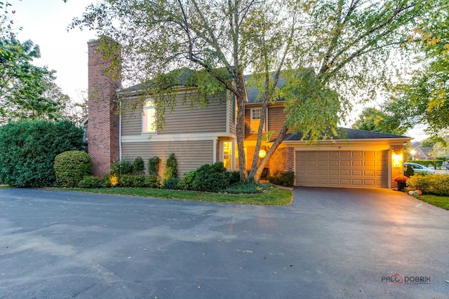 view of front of property with a garage, a chimney, aphalt driveway, and brick siding