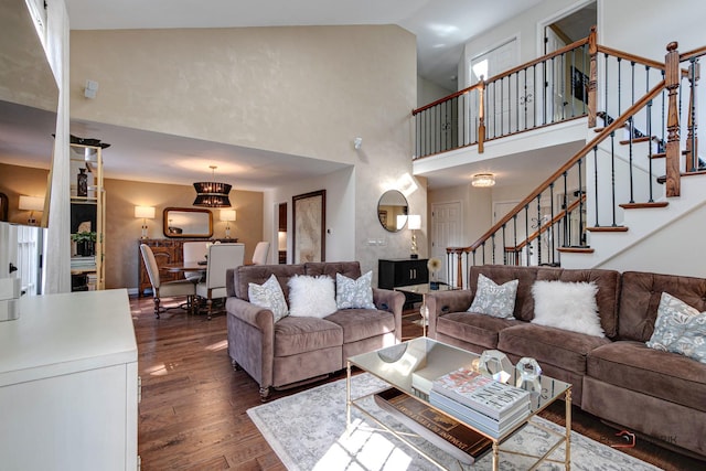 living room with dark wood-type flooring, stairway, and a high ceiling