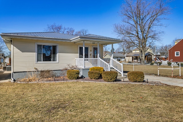 view of front of house with covered porch, metal roof, a front lawn, and cooling unit