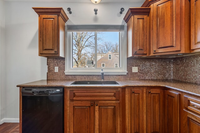 kitchen featuring black dishwasher, brown cabinets, dark countertops, backsplash, and a sink