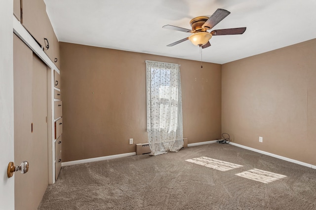 carpeted empty room featuring a ceiling fan and baseboards