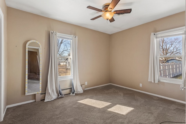 carpeted spare room with a ceiling fan, plenty of natural light, and baseboards