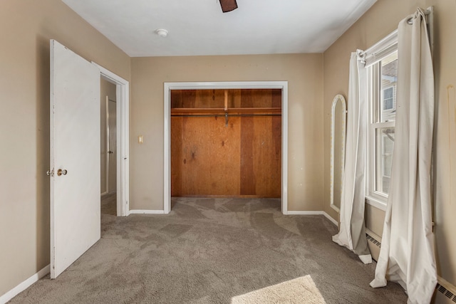 unfurnished bedroom featuring a closet, carpet, a baseboard radiator, and baseboards