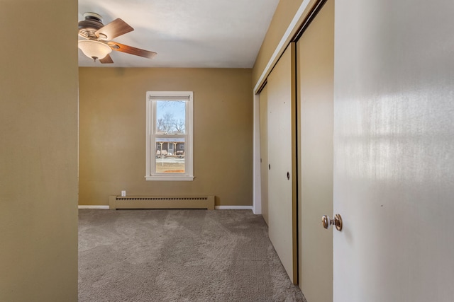 unfurnished bedroom with ceiling fan, a baseboard heating unit, carpet flooring, baseboards, and a closet