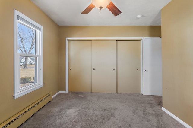 unfurnished bedroom featuring a baseboard radiator, a closet, a ceiling fan, carpet flooring, and baseboards