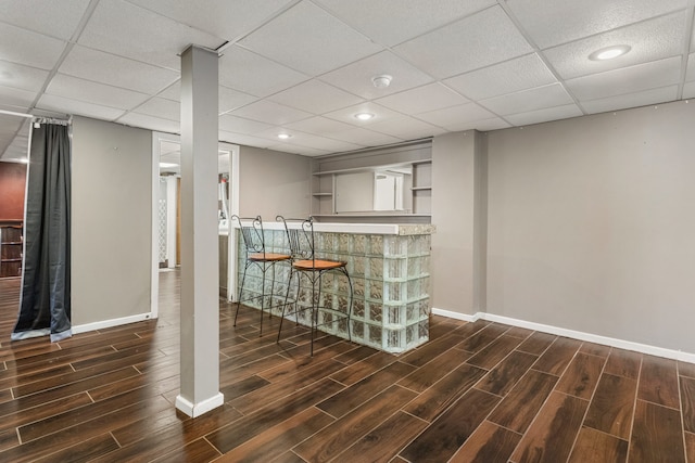 bar with a paneled ceiling, baseboards, a dry bar, and wood finished floors