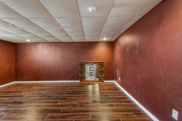 spare room featuring wood tiled floor, a paneled ceiling, and baseboards