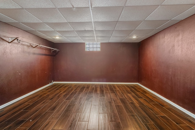 basement featuring a drop ceiling, wood finished floors, and baseboards