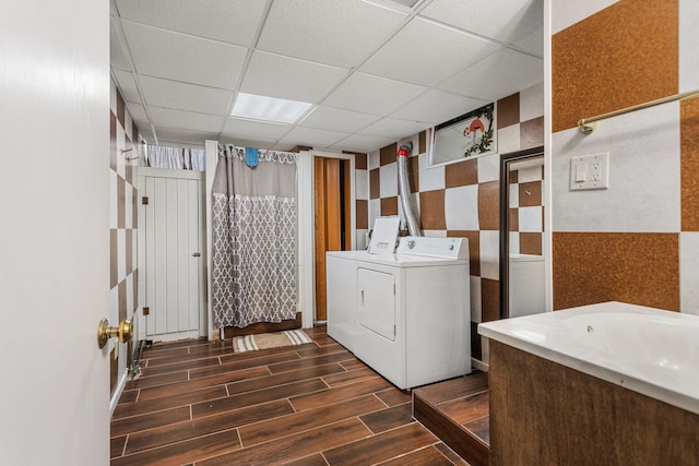 clothes washing area featuring wood finish floors, laundry area, and washer and clothes dryer