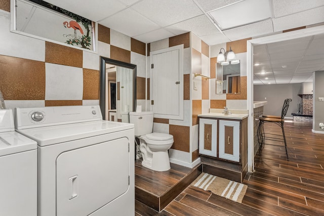 bathroom featuring a drop ceiling, independent washer and dryer, toilet, and wood finished floors