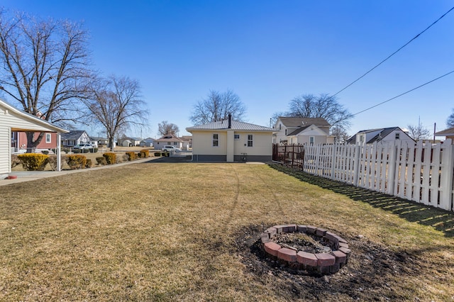 view of yard with an outdoor fire pit, a residential view, and fence