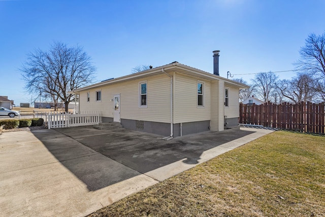 view of property exterior featuring a yard, entry steps, fence, and driveway