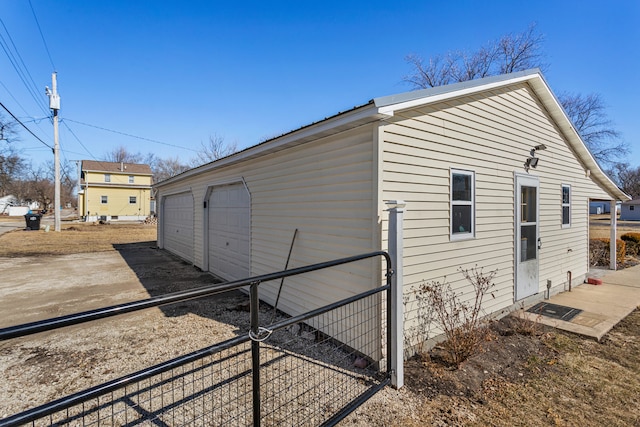 view of home's exterior with an outbuilding, a detached garage, and fence