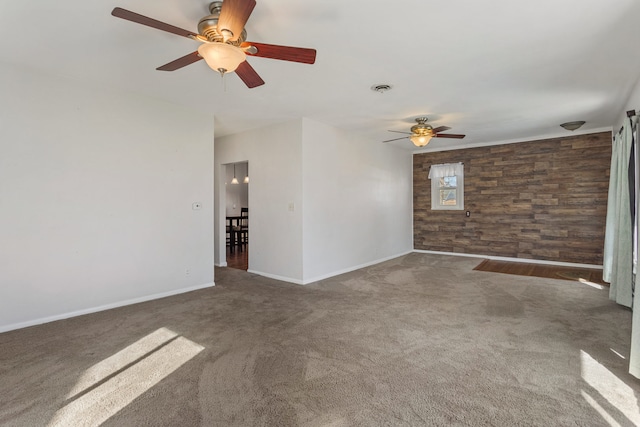 carpeted spare room featuring visible vents, wooden walls, and baseboards