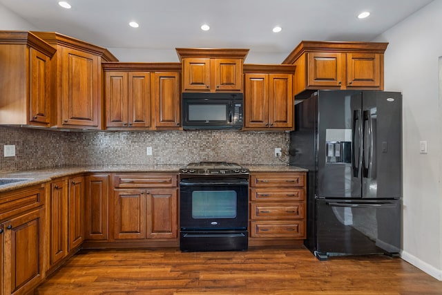 kitchen with black appliances, brown cabinets, and dark wood-type flooring