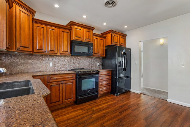 kitchen with a sink, visible vents, backsplash, dark wood-style floors, and black appliances