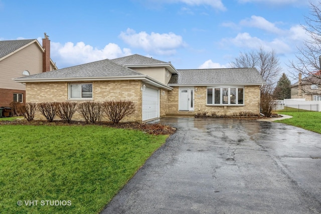 view of front of house with an attached garage, brick siding, fence, driveway, and a front yard