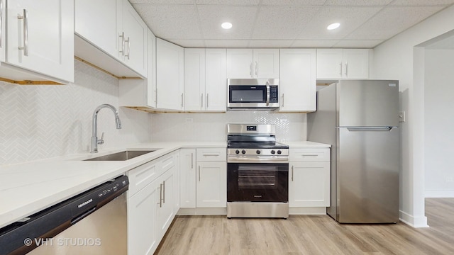 kitchen featuring stainless steel appliances, light wood-type flooring, a sink, and white cabinets