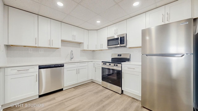 kitchen featuring white cabinets, stainless steel appliances, a sink, and light countertops