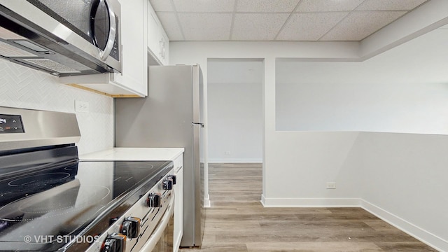 kitchen featuring light wood finished floors, tasteful backsplash, appliances with stainless steel finishes, and white cabinets