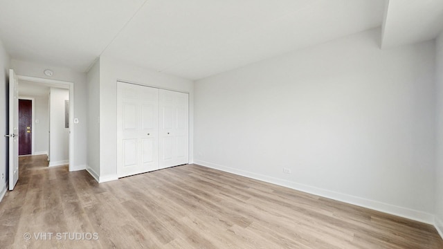 unfurnished bedroom with light wood-style floors, a closet, and baseboards