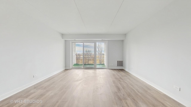 empty room featuring light wood-type flooring, visible vents, and baseboards