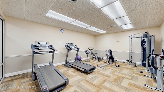 workout area featuring a paneled ceiling, visible vents, and baseboards