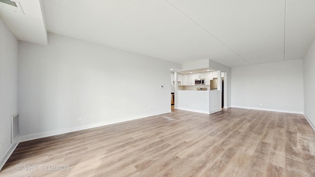 unfurnished living room featuring light wood finished floors, baseboards, and visible vents