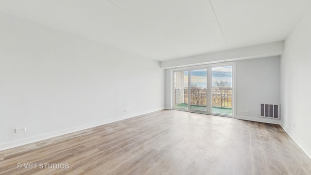 spare room with wood finished floors, visible vents, and baseboards