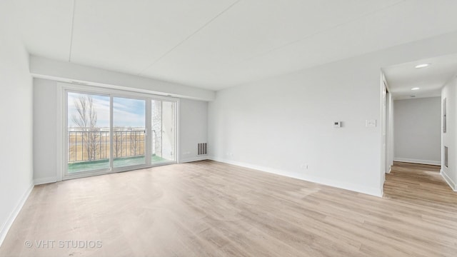 spare room featuring light wood-type flooring, visible vents, and baseboards