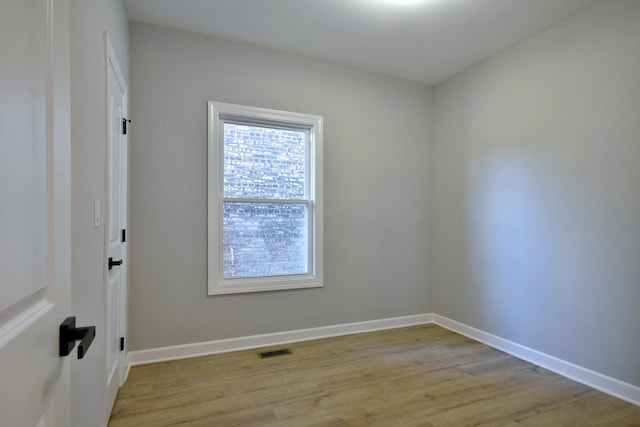 empty room with light wood-type flooring, visible vents, and baseboards