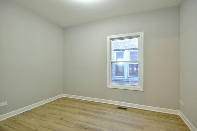 empty room featuring light wood-style flooring, visible vents, and baseboards