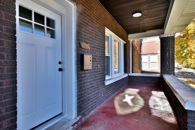 doorway to property featuring brick siding and a porch