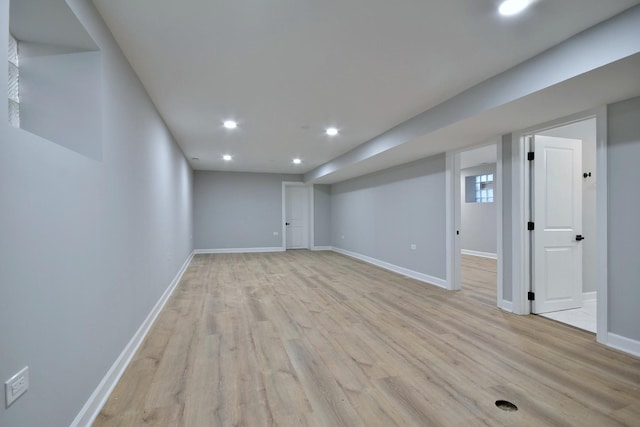 finished below grade area featuring light wood finished floors, recessed lighting, and baseboards