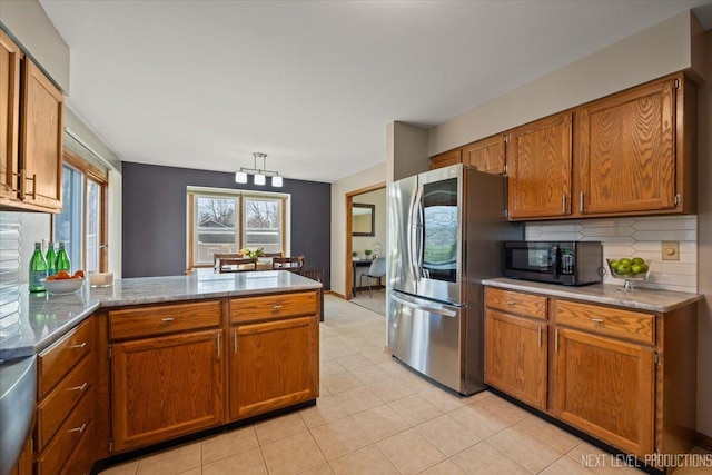 kitchen with backsplash, refrigerator with glass door, brown cabinetry, black microwave, and a peninsula