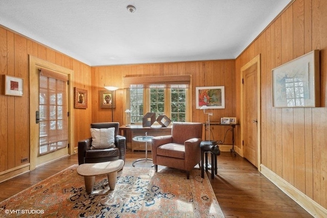 sitting room with wood walls, wood finished floors, and baseboards