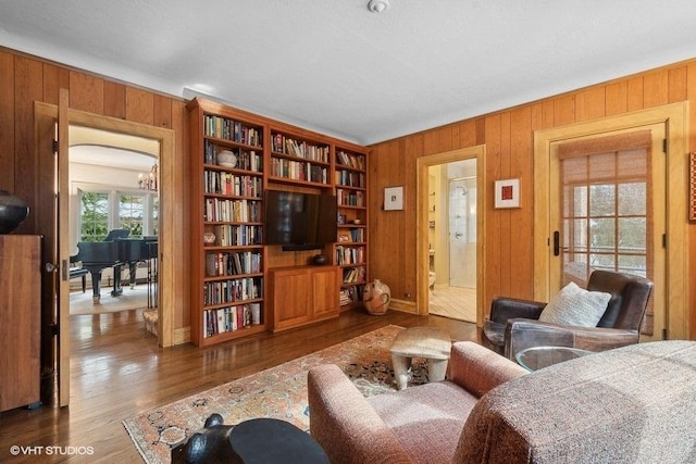 living room featuring wood walls, an inviting chandelier, and wood finished floors