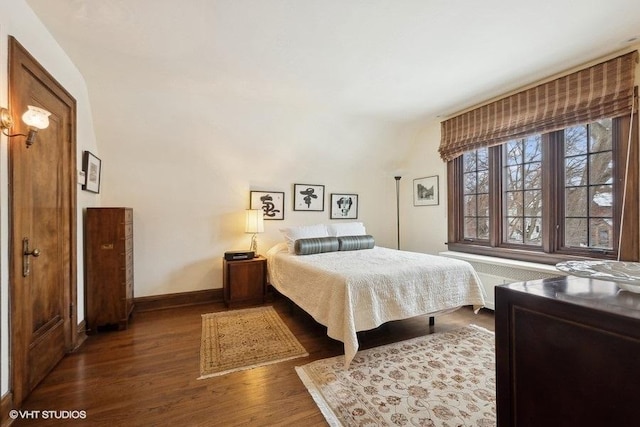 bedroom with radiator heating unit, baseboards, and dark wood-type flooring