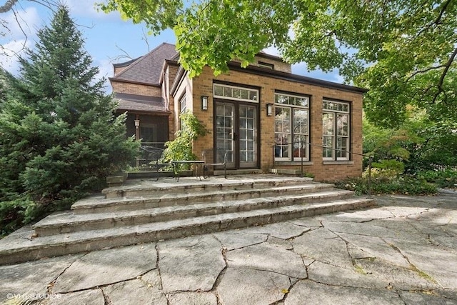 view of front facade featuring brick siding and french doors