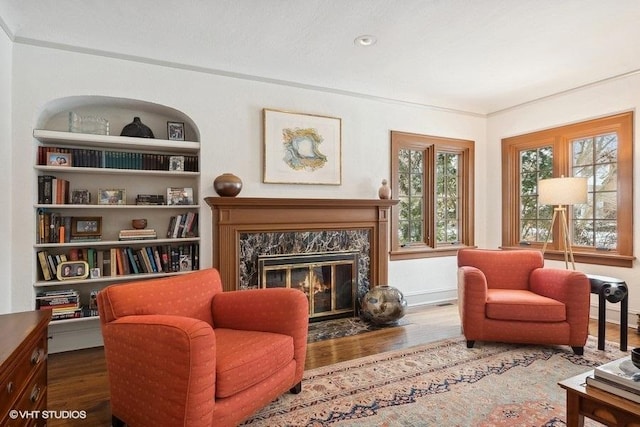 sitting room with baseboards, built in features, wood finished floors, and a high end fireplace