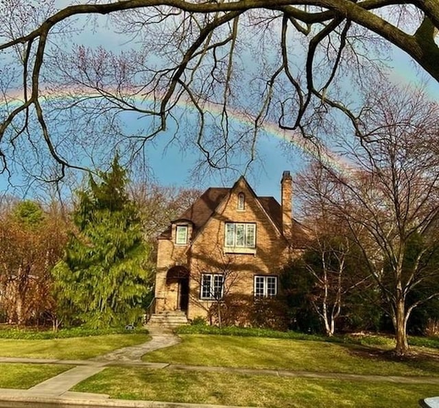 english style home with a front lawn and a chimney