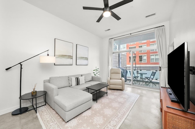 living room with finished concrete flooring, ceiling fan, visible vents, and baseboards